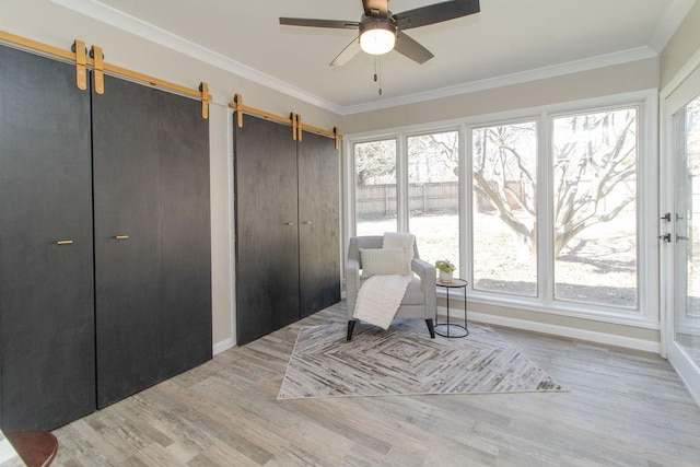 living area featuring ornamental molding, a barn door, and light hardwood / wood-style floors