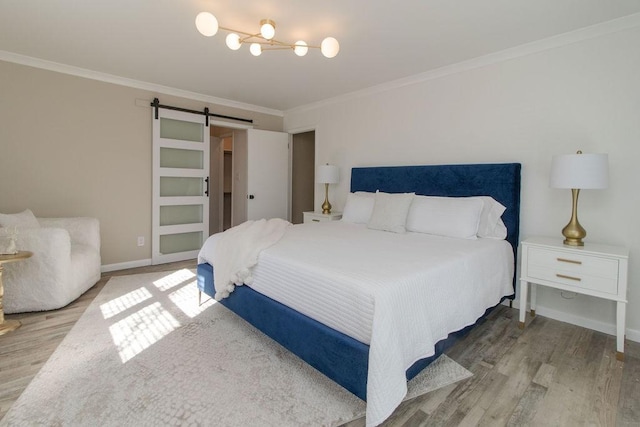 bedroom with light hardwood / wood-style floors, ornamental molding, and a barn door