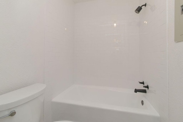 bathroom featuring tiled shower / bath combo and toilet