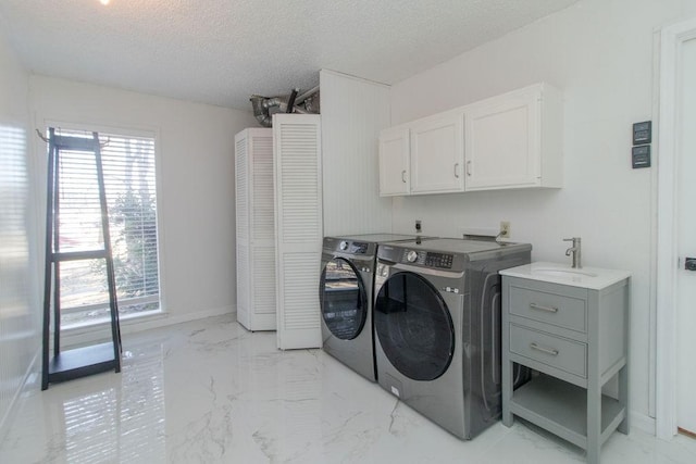 clothes washing area featuring sink, washing machine and dryer, cabinets, and a healthy amount of sunlight