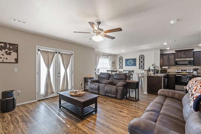 living room featuring hardwood / wood-style flooring, ceiling fan, and a textured ceiling