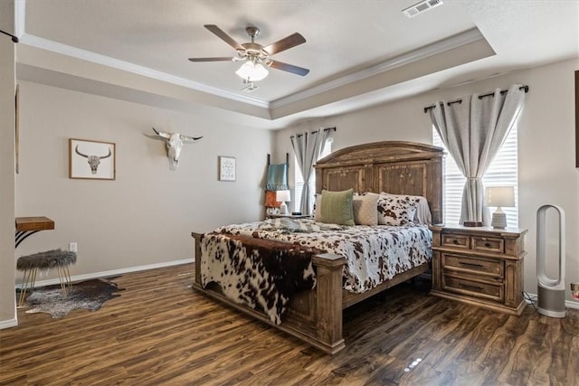 bedroom with crown molding, dark hardwood / wood-style floors, and a raised ceiling