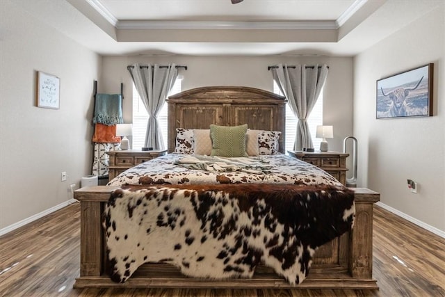 bedroom with ornamental molding, dark hardwood / wood-style flooring, and a tray ceiling