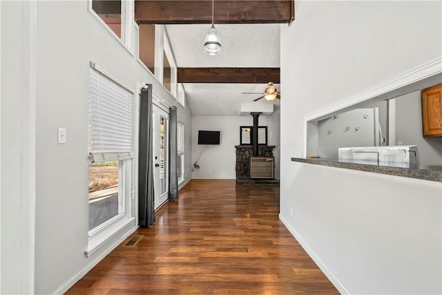 hallway featuring dark wood-type flooring, beam ceiling, and a towering ceiling