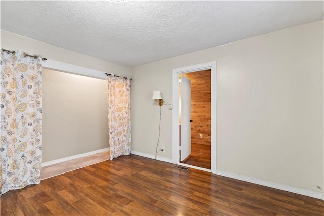 unfurnished room featuring dark wood-type flooring and a textured ceiling