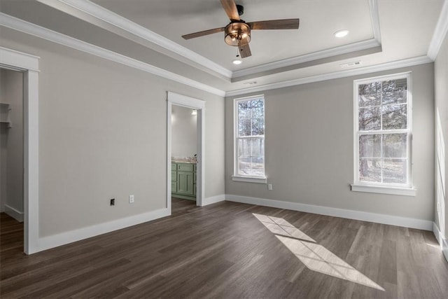 unfurnished bedroom featuring a raised ceiling, crown molding, dark hardwood / wood-style floors, and ensuite bathroom