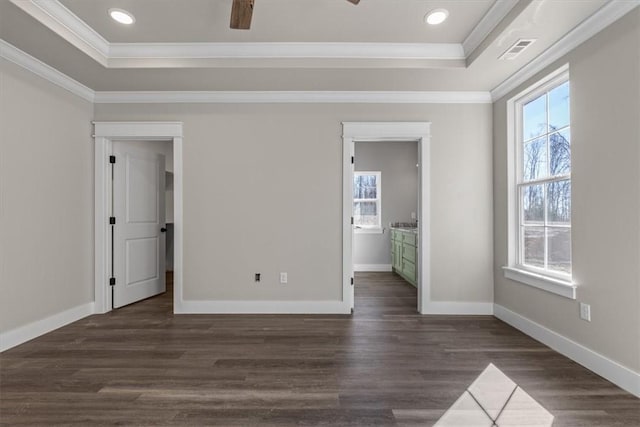 unfurnished bedroom with ornamental molding, dark wood-type flooring, and a tray ceiling