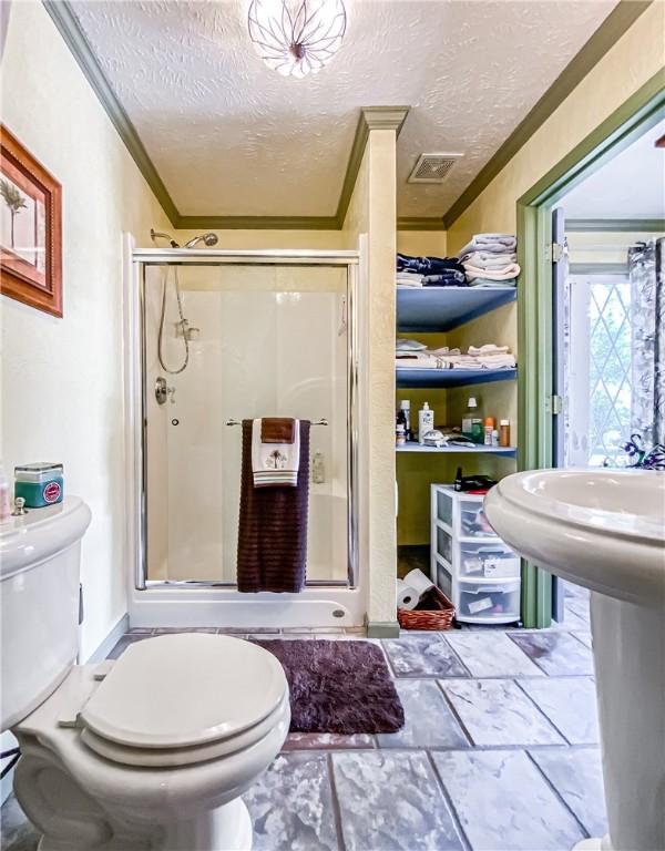 bathroom featuring an enclosed shower, crown molding, and a textured ceiling