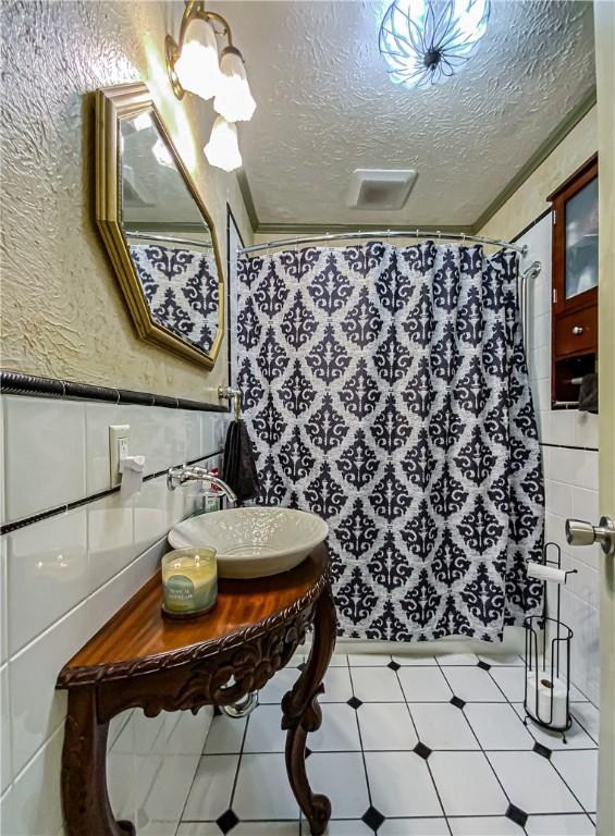 bathroom with sink, tile walls, a textured ceiling, and a shower with curtain