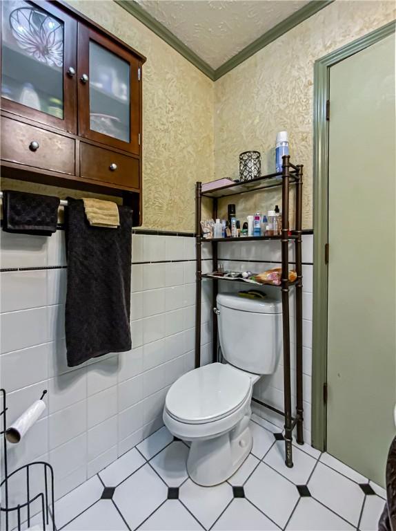 bathroom featuring tile walls, a textured ceiling, ornamental molding, and toilet