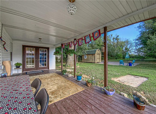 wooden terrace featuring french doors, a lawn, and a shed