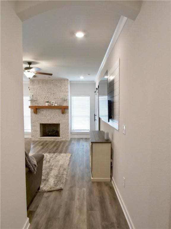 living room with hardwood / wood-style flooring, crown molding, a fireplace, and ceiling fan