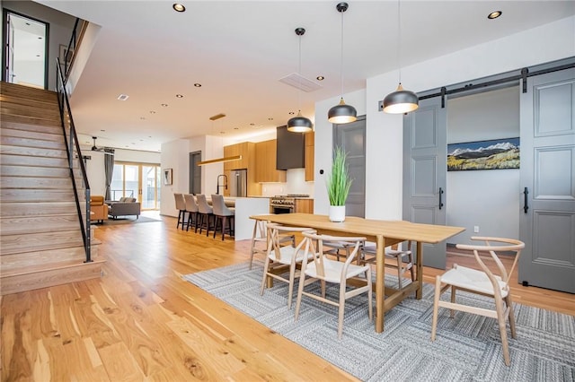 dining room with light hardwood / wood-style floors and a barn door