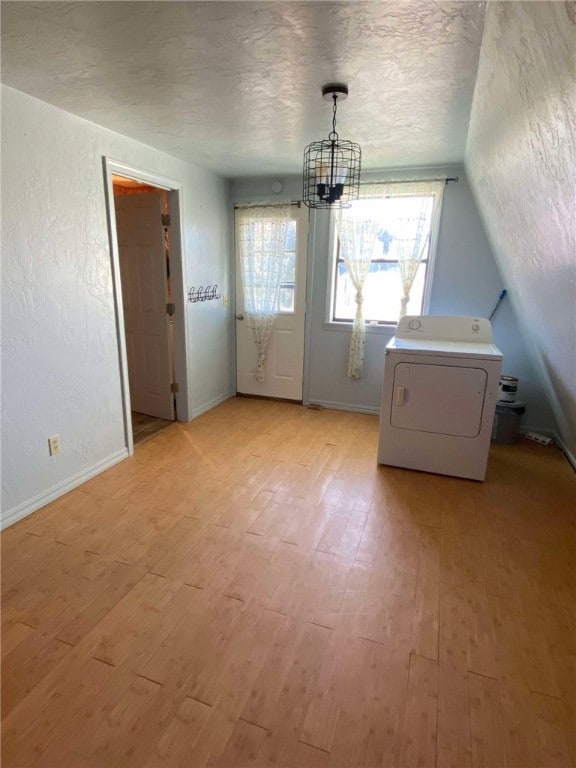 interior space with washer / dryer, light wood-type flooring, an inviting chandelier, and a textured ceiling