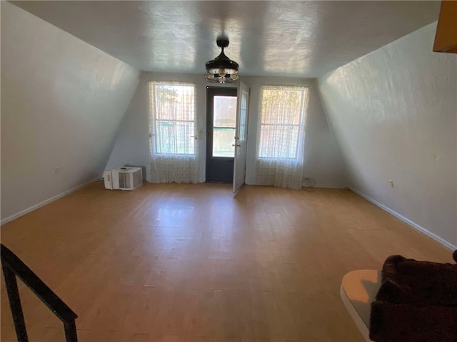 additional living space with lofted ceiling, hardwood / wood-style floors, and a textured ceiling