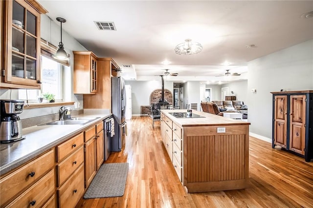 kitchen with appliances with stainless steel finishes, decorative light fixtures, sink, a wood stove, and a center island