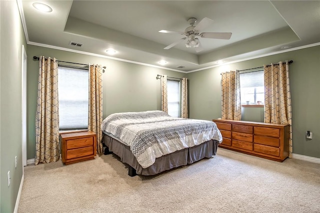 carpeted bedroom with crown molding, a tray ceiling, and ceiling fan