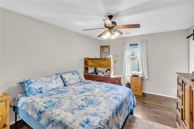 bedroom with dark wood-type flooring, ceiling fan, a barn door, and a textured ceiling