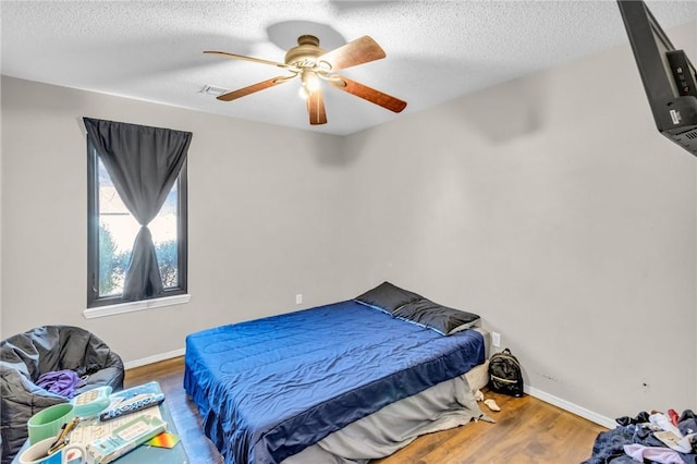 bedroom with hardwood / wood-style floors, a textured ceiling, and ceiling fan