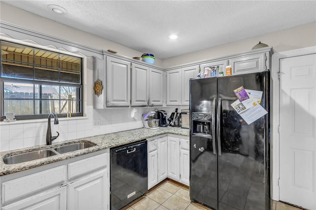 kitchen with light tile patterned flooring, sink, black appliances, light stone countertops, and backsplash