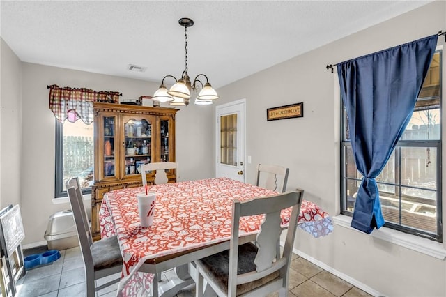 tiled dining area with a notable chandelier and a textured ceiling