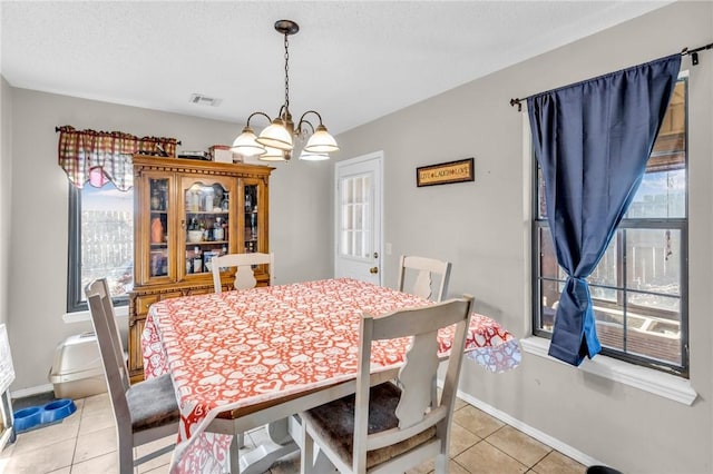 dining space with an inviting chandelier, light tile patterned floors, and a textured ceiling