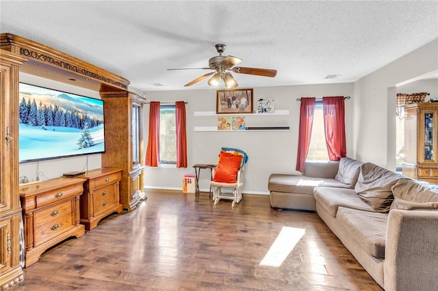 living room featuring ceiling fan, dark wood-type flooring, and a textured ceiling