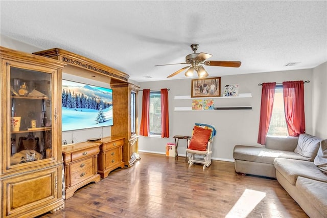 living room with ceiling fan, dark hardwood / wood-style floors, a wealth of natural light, and a textured ceiling