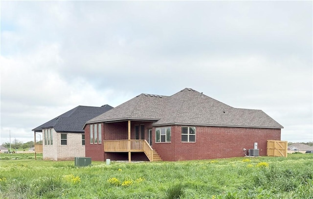 rear view of property featuring central AC, brick siding, roof with shingles, and stairs