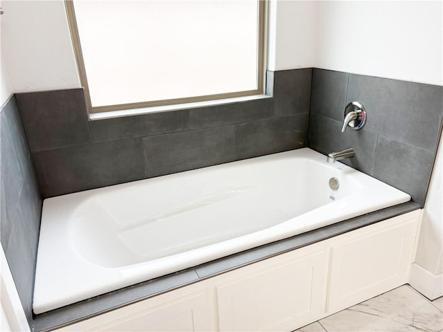 full bath featuring a bath and marble finish floor