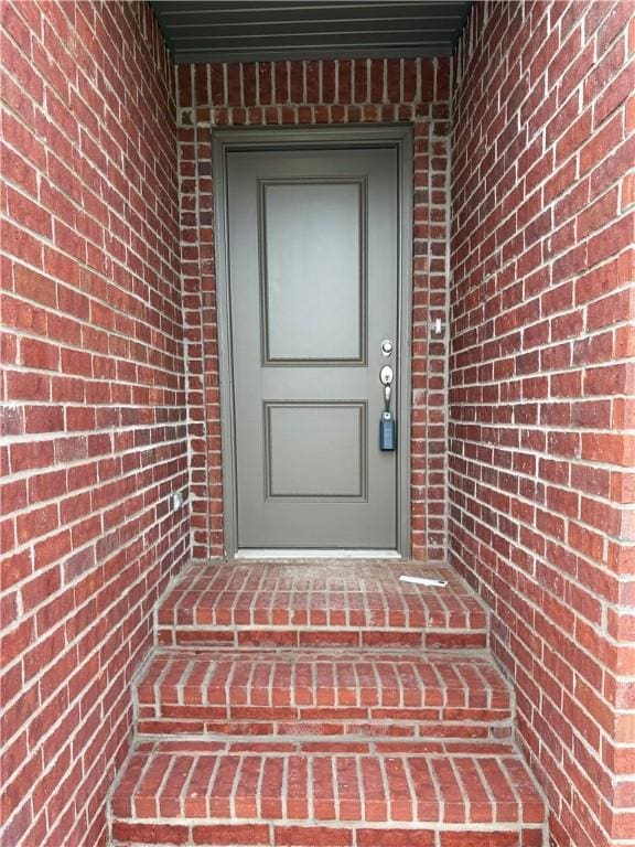 entrance to property featuring brick siding