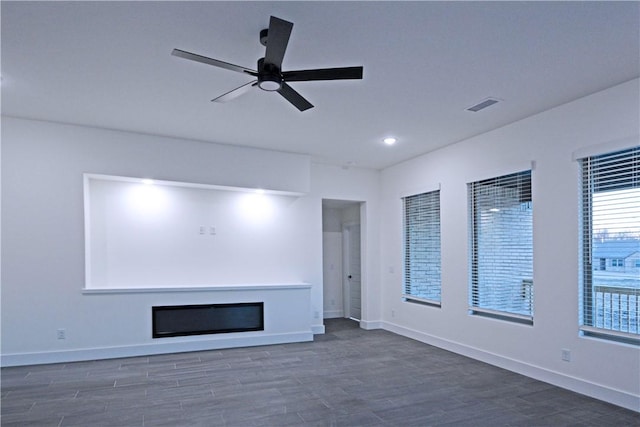 unfurnished living room featuring dark wood-type flooring and ceiling fan