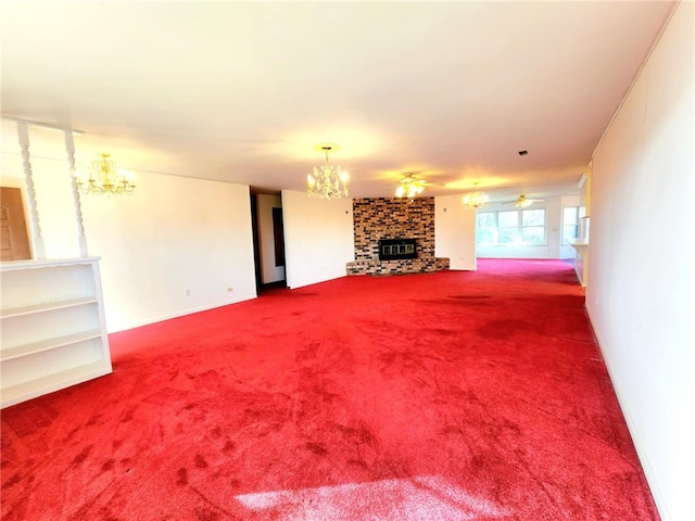 unfurnished living room with a stone fireplace, ceiling fan with notable chandelier, and carpet