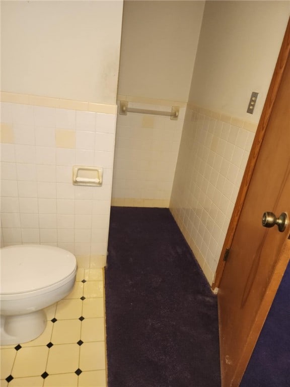 bathroom featuring tile walls, tile patterned flooring, and toilet