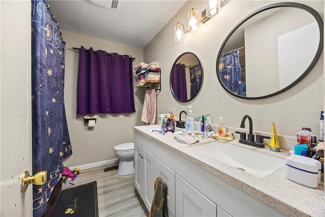 full bath with visible vents, baseboards, toilet, wood finished floors, and vanity