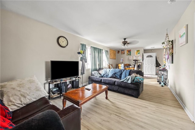 living area with light wood-type flooring, ceiling fan, and baseboards