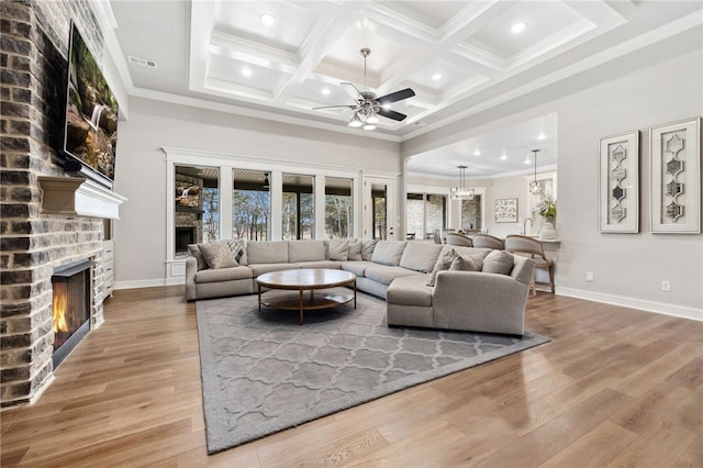 living room featuring coffered ceiling, crown molding, a brick fireplace, light hardwood / wood-style flooring, and beamed ceiling