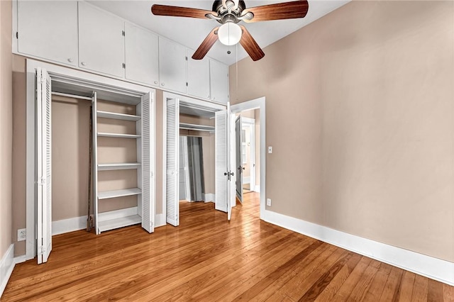 unfurnished bedroom with ceiling fan, light hardwood / wood-style floors, and two closets