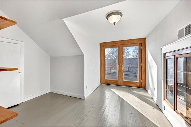 bonus room with hardwood / wood-style flooring, vaulted ceiling, and french doors