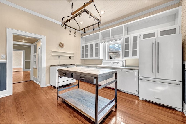 kitchen featuring white cabinetry, sink, premium appliances, crown molding, and light wood-type flooring