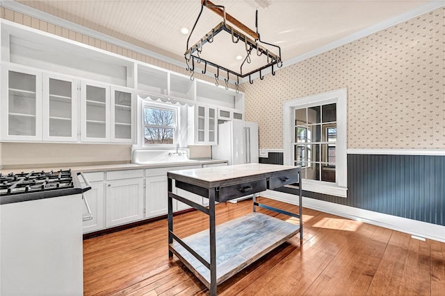 kitchen with sink, light hardwood / wood-style flooring, white refrigerator, ornamental molding, and white cabinets