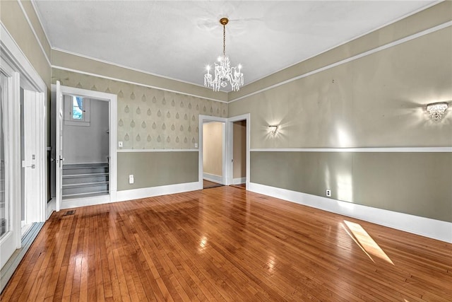 unfurnished room featuring crown molding, hardwood / wood-style floors, and a notable chandelier