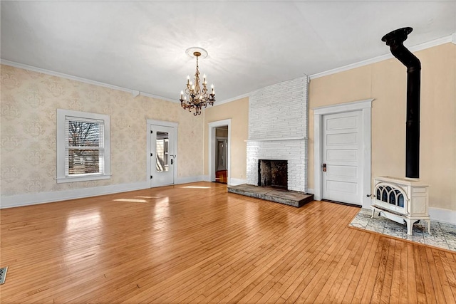 unfurnished living room featuring a fireplace, ornamental molding, light hardwood / wood-style floors, and a wood stove