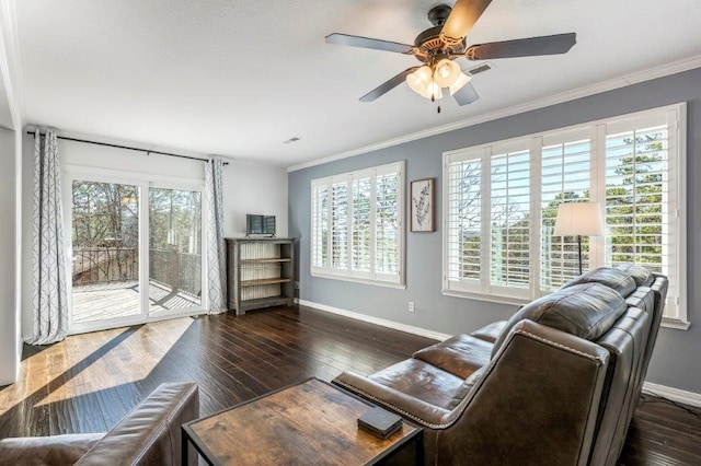 living room with dark wood-type flooring, ornamental molding, ceiling fan, and plenty of natural light