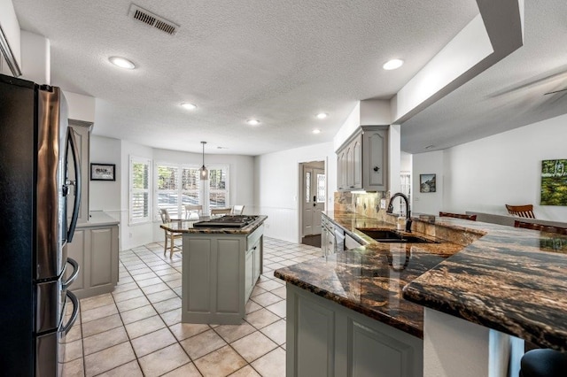 kitchen with pendant lighting, sink, gray cabinets, stainless steel appliances, and kitchen peninsula