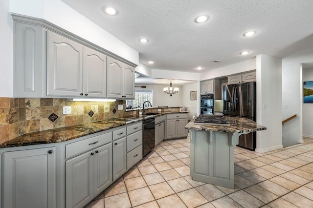 kitchen featuring dark stone countertops, sink, hanging light fixtures, and gray cabinetry