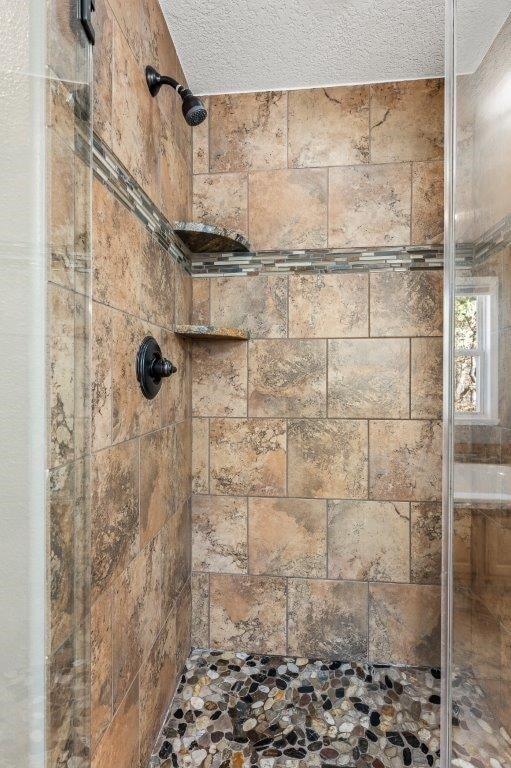 details with a textured ceiling and tiled shower