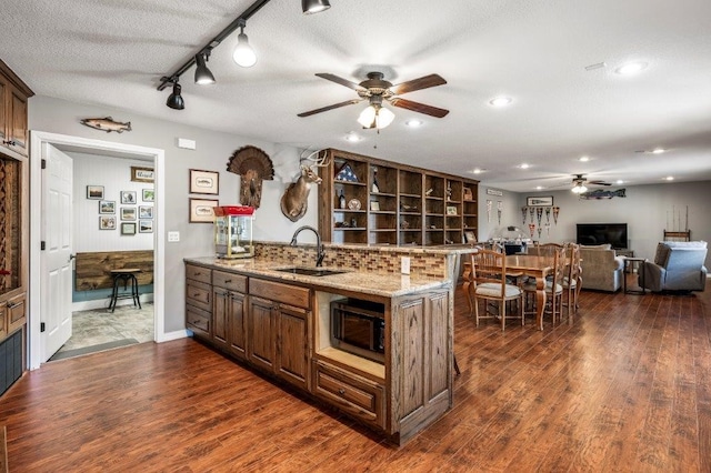 kitchen featuring sink, light stone counters, dark hardwood / wood-style floors, kitchen peninsula, and ceiling fan