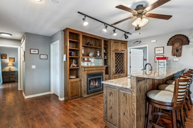 bar featuring a textured ceiling, light stone countertops, dark hardwood / wood-style floors, and ceiling fan