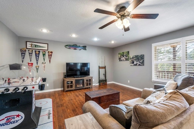 living room with ceiling fan, dark hardwood / wood-style floors, and a textured ceiling